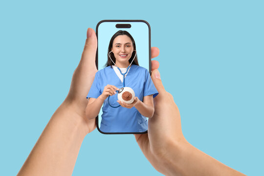 Female doctor with stethoscope listening to knitted breast model on blue background