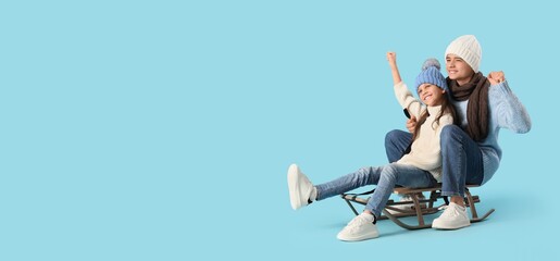 Happy brother and sister in winter hats sledding on blue background with space for text