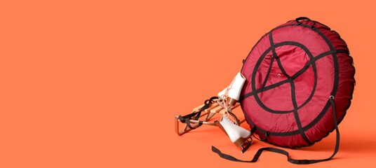 Snow tube with sled and ice skates on orange background with space for text