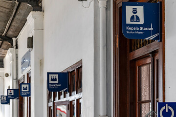 Historic Indonesian Railway Station Interior with Bilingual Directional Signage and Wooden Doors