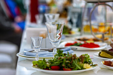 A table with a variety of food and drinks including a salad and wine glasses