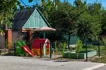 A playground with a green house and a red slide