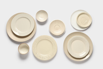 Set of beige plates and bowls on white background