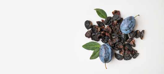 Dried plum prunes and fresh plums with green leaves on gray background flat lay top view. Food background, dried delicious fruits, sweet healthy dessert, healthy eating