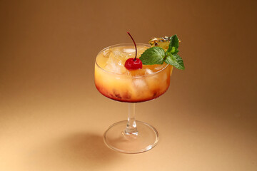 Glass of tasty Mai Tai cocktail garnished with cherry and mint on brown background
