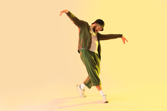 Handsome young man dancing hip-hop on yellow background