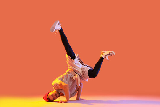 Handsome young man dancing hip-hop on orange background - Powered by Adobe
