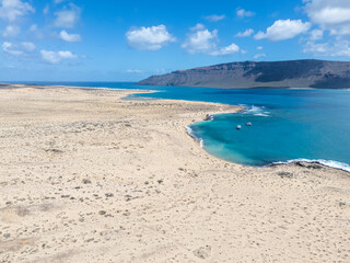 Aerial view of volcanic cones and arid landscape on La Graciosa Island, Canary Islands, with distant views of surrounding islands and the Atlantic Ocean.
