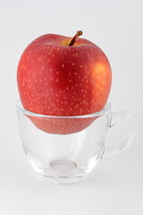 red apple in a transparent coffee cup on a white background