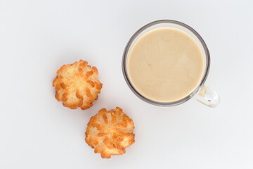 Coffee with milk, cappuccino in a glass transparent cup and two cookies on a white background, top view