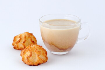 Coffee with milk, cappuccino in a glass transparent cup and two cookies on a white background