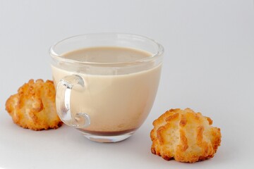 Coffee with milk, cappuccino in a glass transparent cup and two cookies on a white background