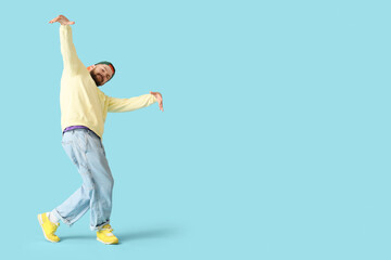 Handsome young man dancing hip-hop on blue background