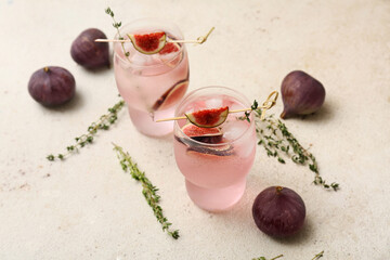 Glasses of fresh fig lemonade on white grunge background, closeup