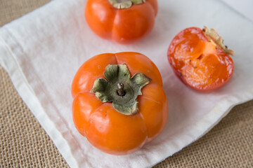  Fresh persimmons on a textile napkin, studio close-up