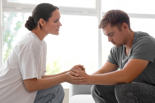 Young woman supporting sad man with suicidal thoughts at home - Powered by Adobe