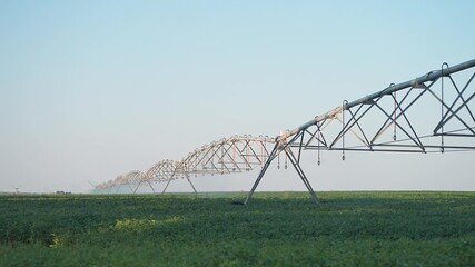 Agriculture sprinkler machine spans wide field to deliver irrigation. Technology improves green farming with steady crop watering. Sprinkler system ensures consistent field irrigation efficiency