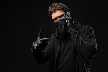 Male fraudster talking by mobile phone on black background