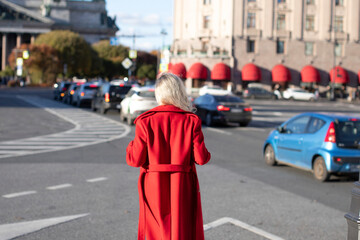 Stylish blonde hair woman in red coat walking on the street
