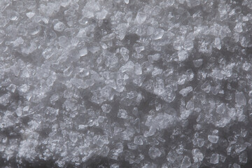 Fototapeta premium Coarse gray salt crystals forming a textured background, showing mineral structure and organic crystalline pattern