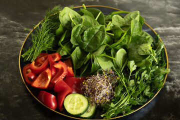 Bowl with fresh vegetables and greens &mdash; spinach, red bell pepper, cucumber, dill and sprouts. Healthy eating, vegetarian food, detox and fitness diet concept.