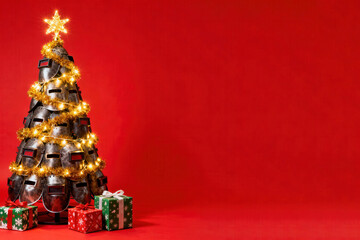 A creative Christmas tree crafted from welder masks adorned with a golden garland and star, surrounded by gifts on a festive red background for industrial holiday campaigns