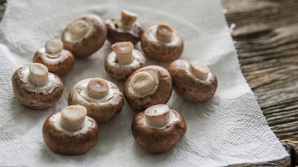 Fresh brown mushrooms arranged on a white paper towel ready for cooking in a rustic kitchen setting