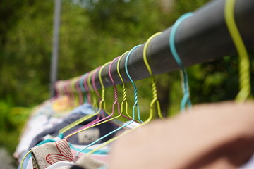 Colorful clothes hangers on a rack with clothes drying outdoors.