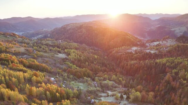 Ukraine, drone, flight in the Carpathians early in the autumn morning at sunrise near the city of Kosiv. Bright forests and dwellings of the Hutsul highlanders on the glades