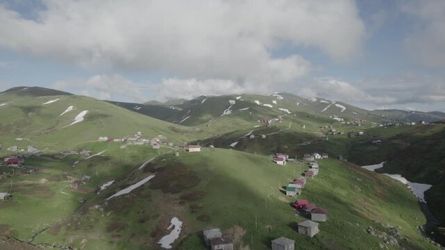 Aerial drone view of Gomis Mta in Georgia, a mountain village with small wooden houses surrounded by snow and green hills. Peaceful and scenic highland landscape. .High quality 4k footage