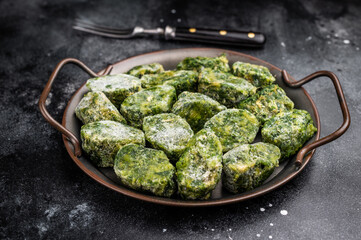Overhead view of frozen spinach blocks in a rustic metal tray with a vintage fork. Dark, textured background with copy space.