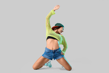 Female hip-hop dancer in cap on light background