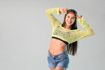 Female hip-hop dancer in cap on light background