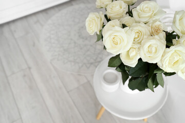 Vase with white roses on table in bathroom, closeup