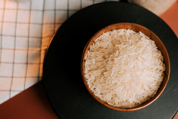 Long grain white rice served in a wooden bowl on a kitchen table with checkered cloth