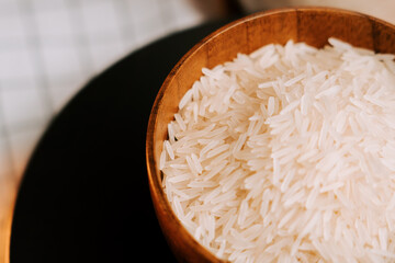 Long grain white rice served in a wooden bowl on a kitchen table with checkered cloth