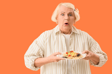 Shocked senior woman with cockroaches in her plate on orange background