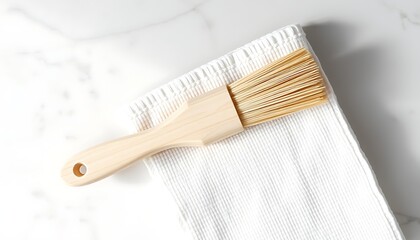 Wooden pastry brush resting on a white textured cloth on a marble surface baking brush cooking brush
