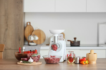 Modern meat grinder and minced beef on table in kitchen