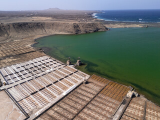Close-up aerial view of traditional salt evaporation ponds with geometric patterns and mineral-rich...