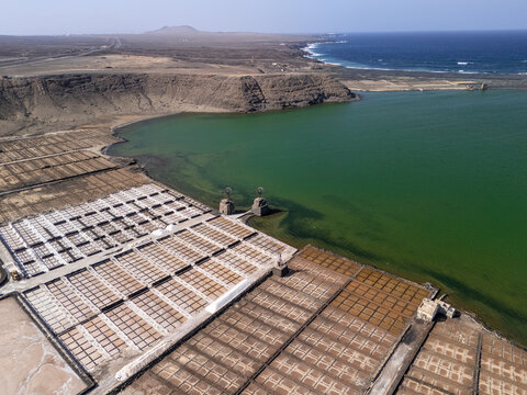 Close-up aerial view of traditional salt evaporation ponds with geometric patterns and mineral-rich brine in Lanzarote, Canary Islands.  
