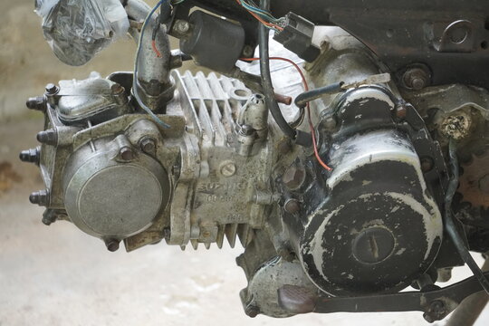 Close-up of a dirty, old motorcycle engine with visible components and wear.