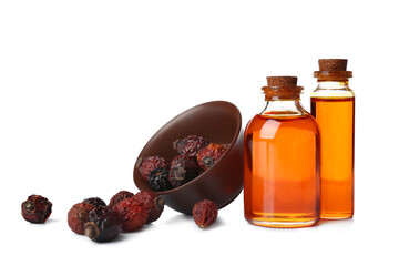 Bottles of cosmetic rose hip oil and bowl with berries on white background