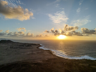 Obraz premium Aerial view of a volcanic cone rising from the arid landscape of La Graciosa Island, Canary Islands, with the Atlantic Ocean in the background. 
