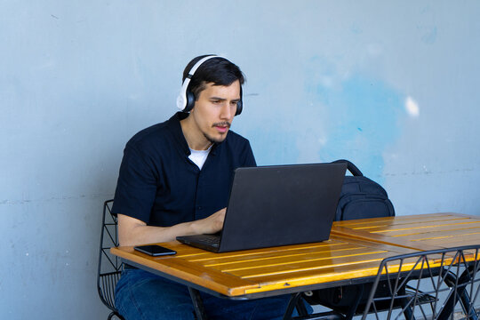 Man working on laptop wearing white headphones