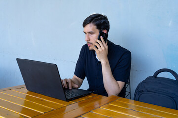 Man multitasking on laptop while making phone call