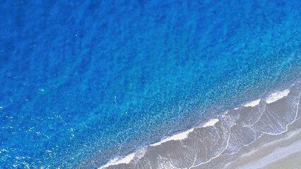 Vibrant Shoreline With Clear Blue Water and Gentle Waves Meets Sandy Beach in Bright Daylight