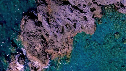 Rocky Shoreline Meets Clear Blue Water in a Coastal Scene Under Bright Sunlight