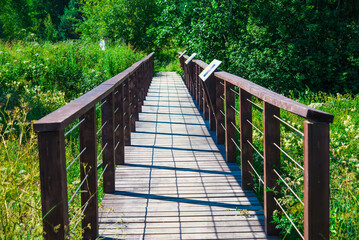 Wooden bridge with railings leading to ecological trail