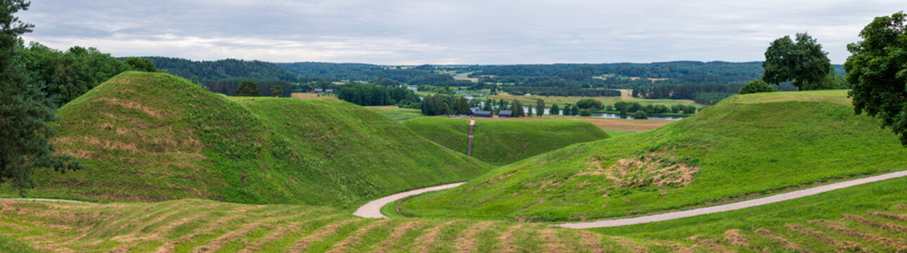 Panoramic view of the Kernave Archaeological Site, Lithuania's former medieval capital, featuring ancient hillforts and the scenic Neris River Valley.